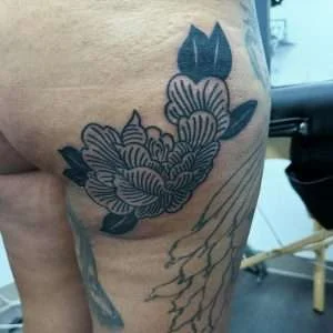 Floral hip and thigh piece in fine-line black and grey, tattooed at Nu Nebula Tattoo