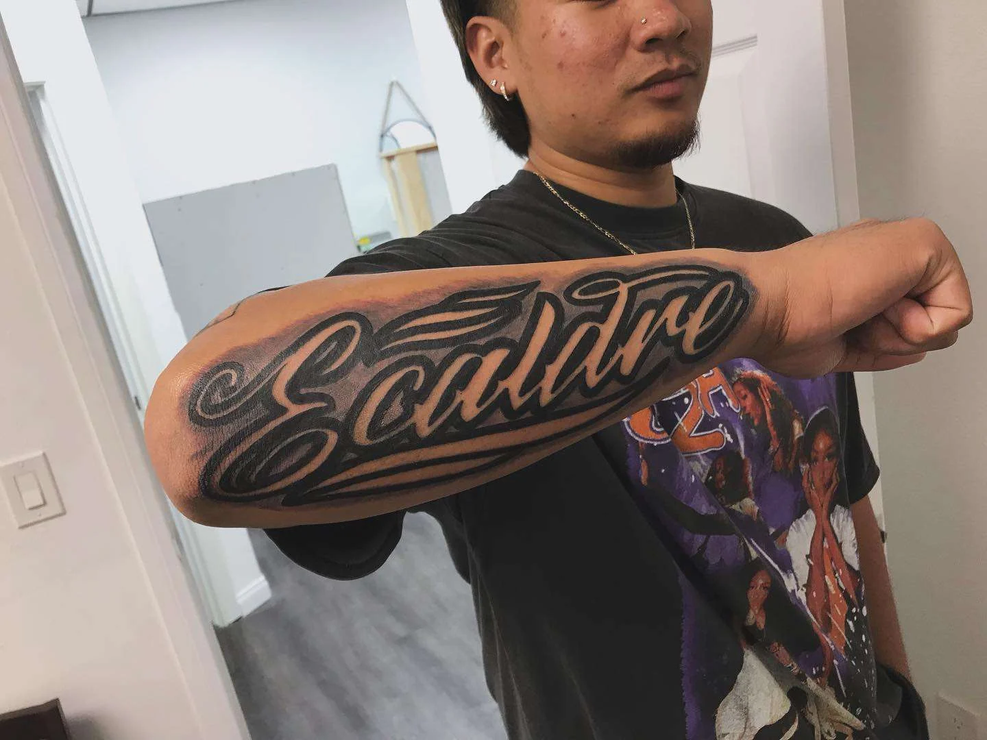 Client showing a freshly finished script tattoo inside the Nu Nebula Tattoo studio