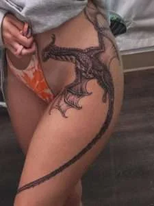 Dragon running down the thigh in fine-line black and grey, tattooed at Nu Nebula Tattoo