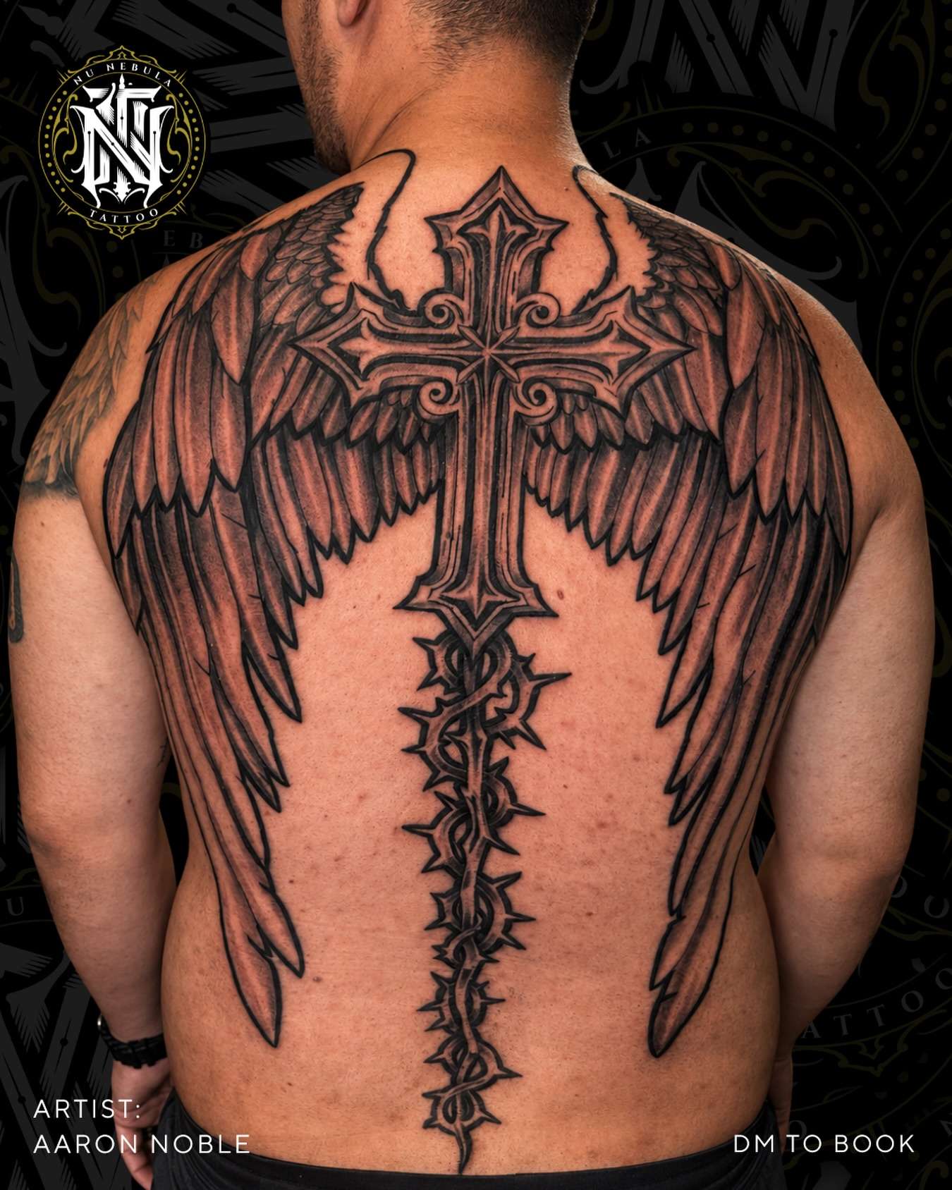Cross and wings back piece in black and grey, tattooed by Aaron Noble