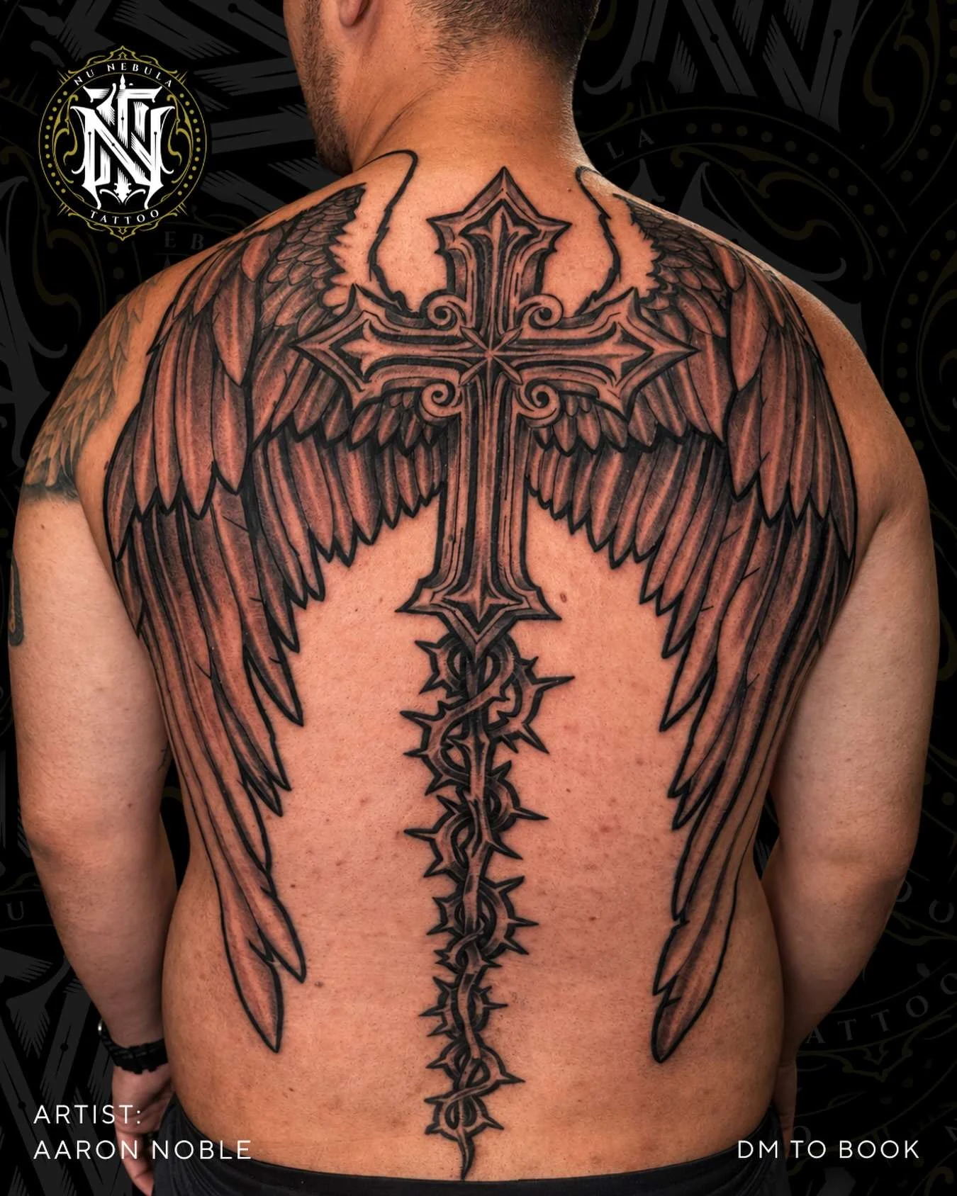 Cross and wings back piece in black and grey, tattooed by Aaron Noble