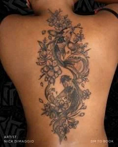 Two koi and cherry blossoms across the back in fine-line black and grey, tattooed by Nick DiMaggio